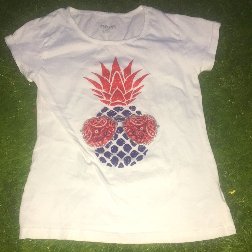 It is a white shirt with a pineapple with sunglasses in the size 12/14.